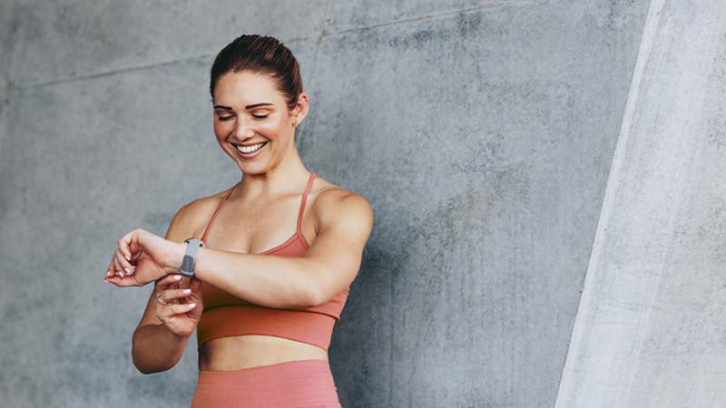 Mulher jovem com roupa de desporto consulta a pulseira desportiva